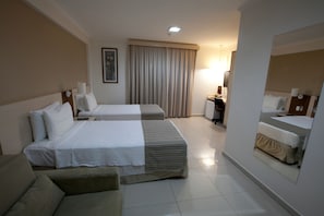 A hotel room with two beds, a sofa, a desk, a lamp, and a large mirror. - Oitis Hotel (Goiania)