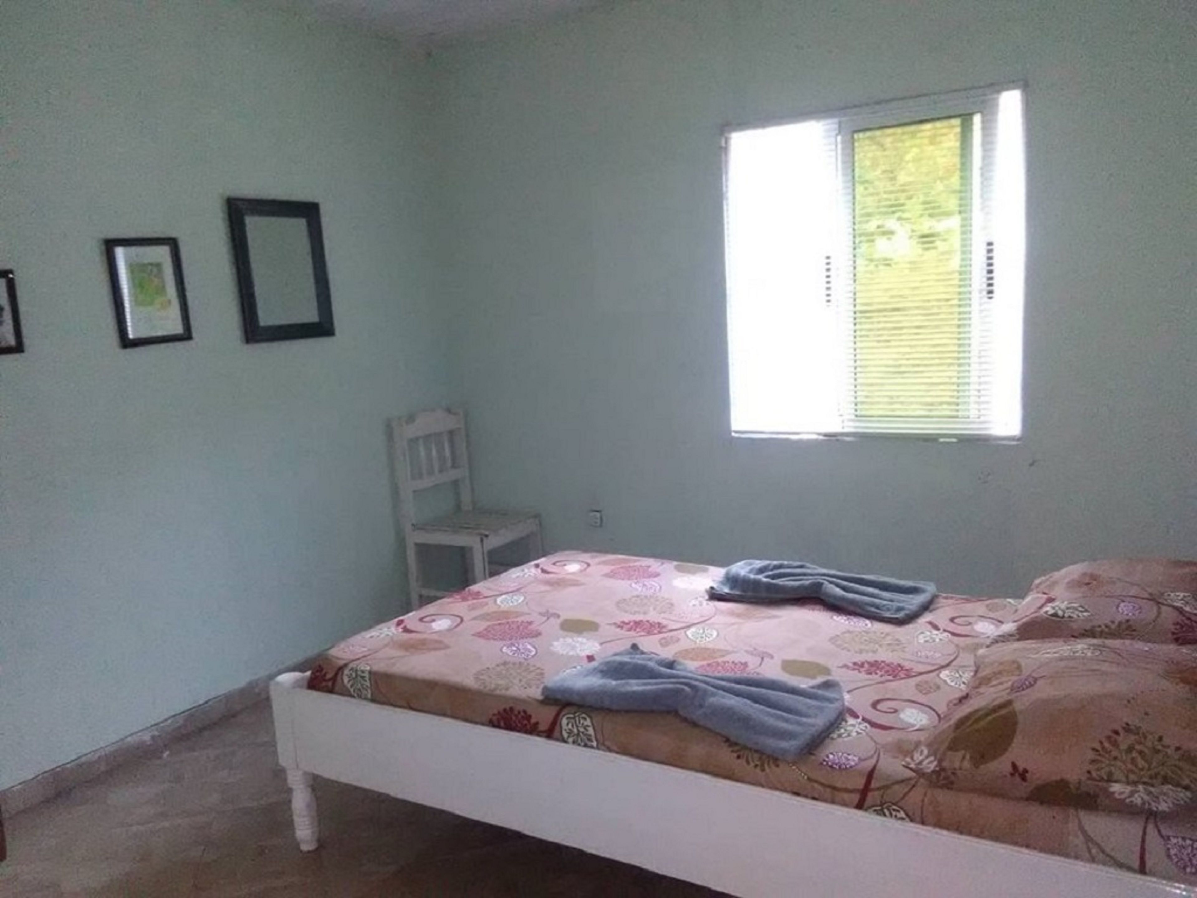 Une chambre à coucher avec un lit, une fenêtre et une chaise.