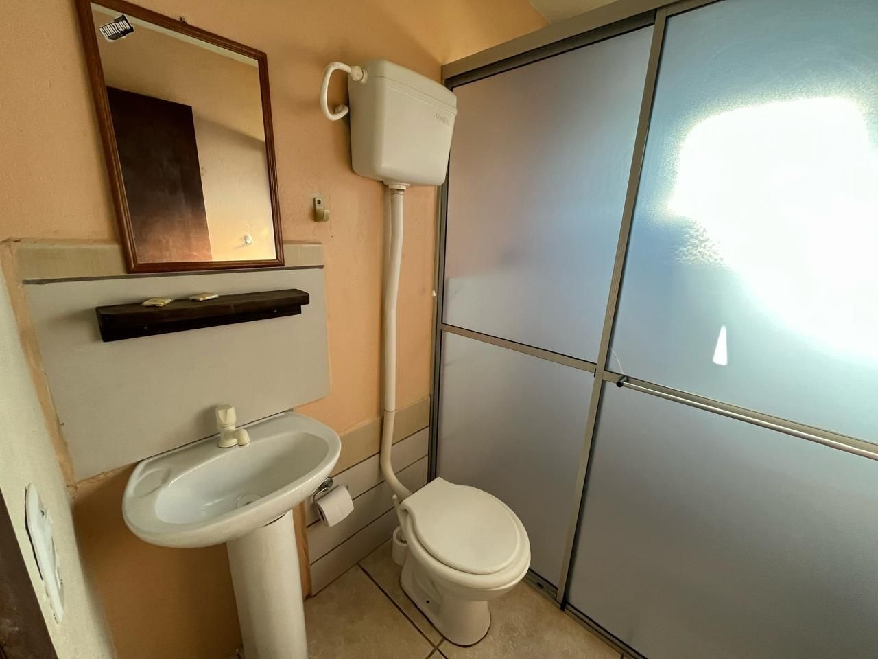 A small bathroom with a toilet, sink, and mirror.