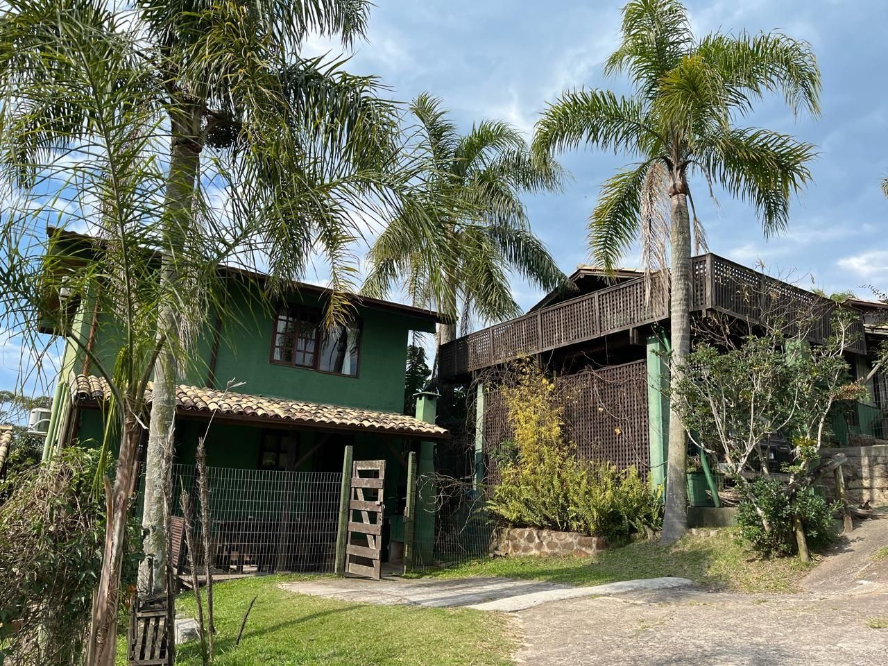 Uma casa verde com telhado de telhas e cerca de madeira.