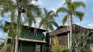 A green house with a tiled roof and a wooden fence. - Pousada Vale Verde Bungalows (Imbituba)