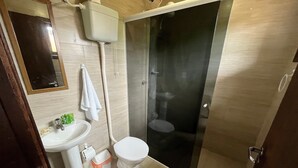 A modern bathroom with a toilet, sink, and shower. - Pousada Vale Verde Bungalows (Imbituba)