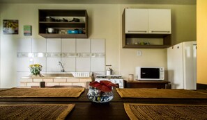 A kitchen with a sink, stove, microwave, and cabinets. - Pousada Vale Verde Bungalows (Imbituba)