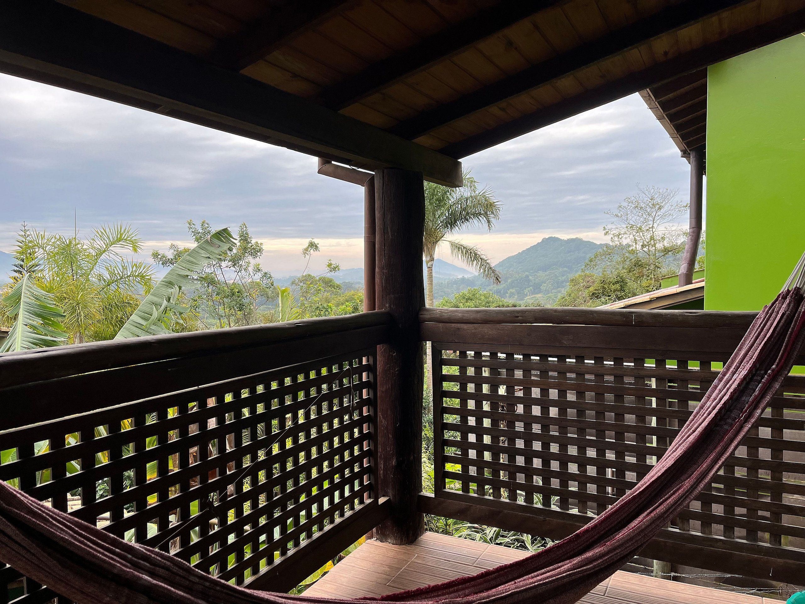A hammock in a wooden structure with a view of mountains and greenery.