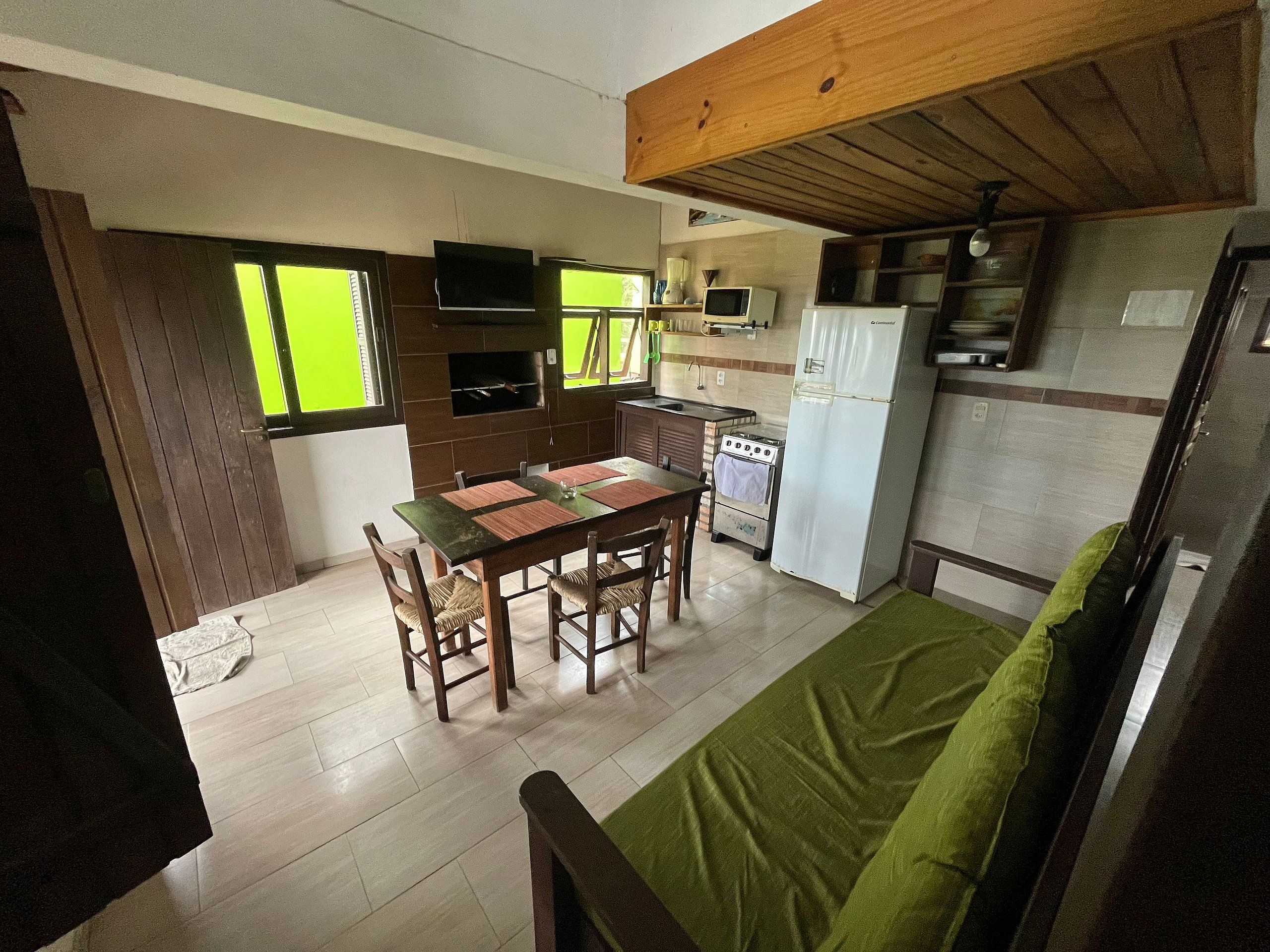 A compact kitchen with a dining table, chairs, a microwave, a stove, and a refrigerator.