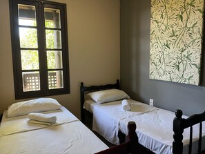 A room with two single beds, a window with a view, and a wall with a bamboo pattern. - Pousada Vale Verde Bungalows (Imbituba)