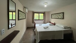 A hotel room with two beds, a bench, a window, and a ceiling light. - Pousada Vale Verde Bungalows (Imbituba)