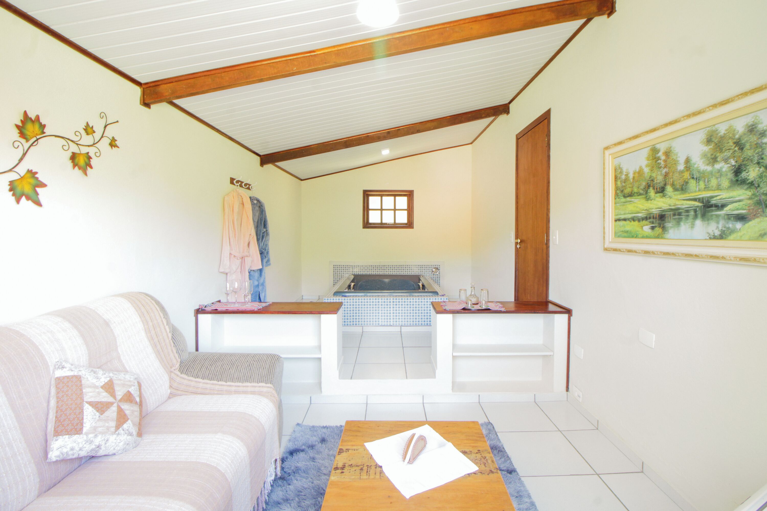 Una habitación acogedora con sofá, una mesita, bañera y un cuadro en la pared.