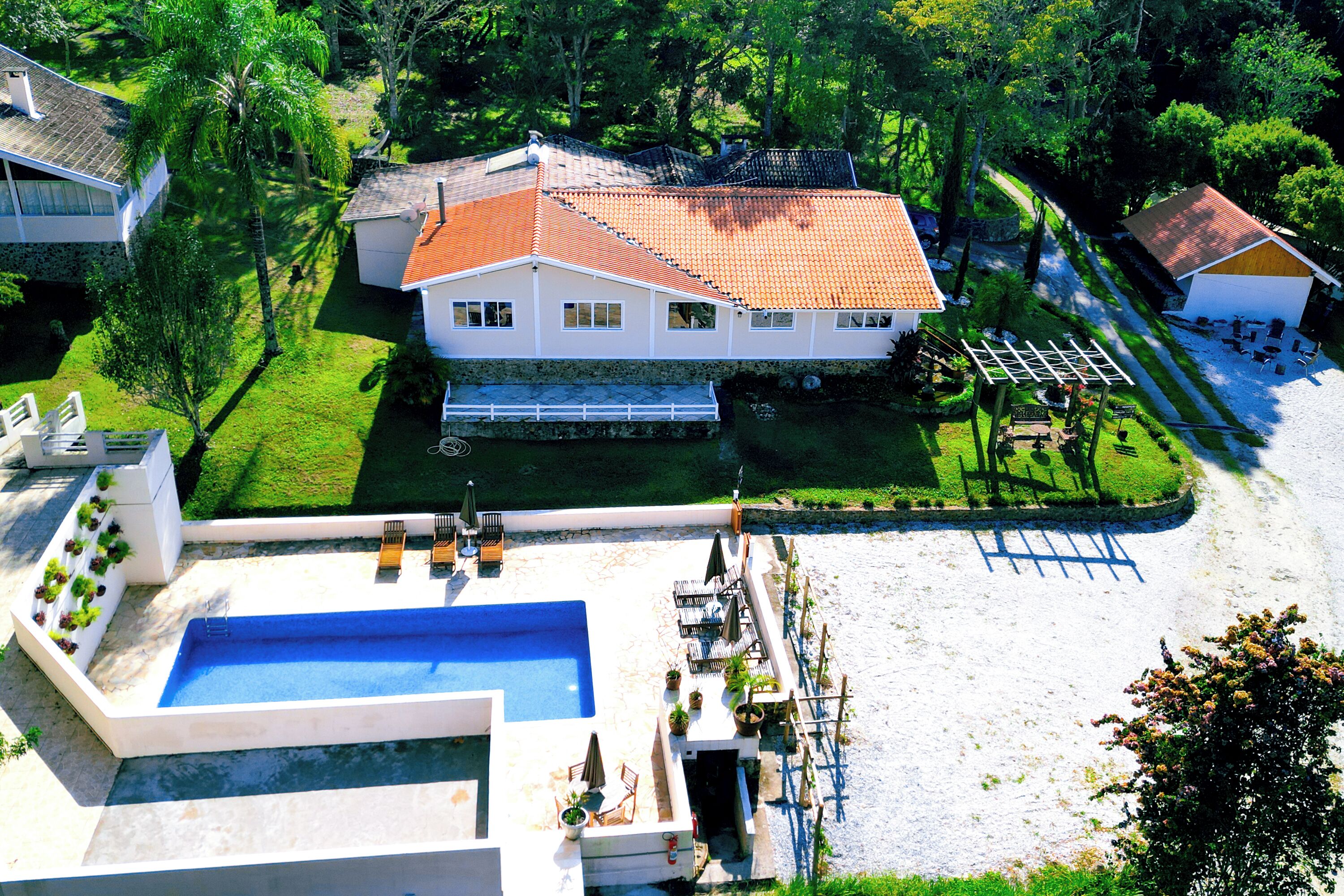 A large house with a swimming pool, a tennis court, and a garden.