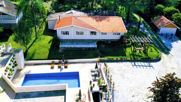 A large house with a swimming pool, a tennis court, and a garden.