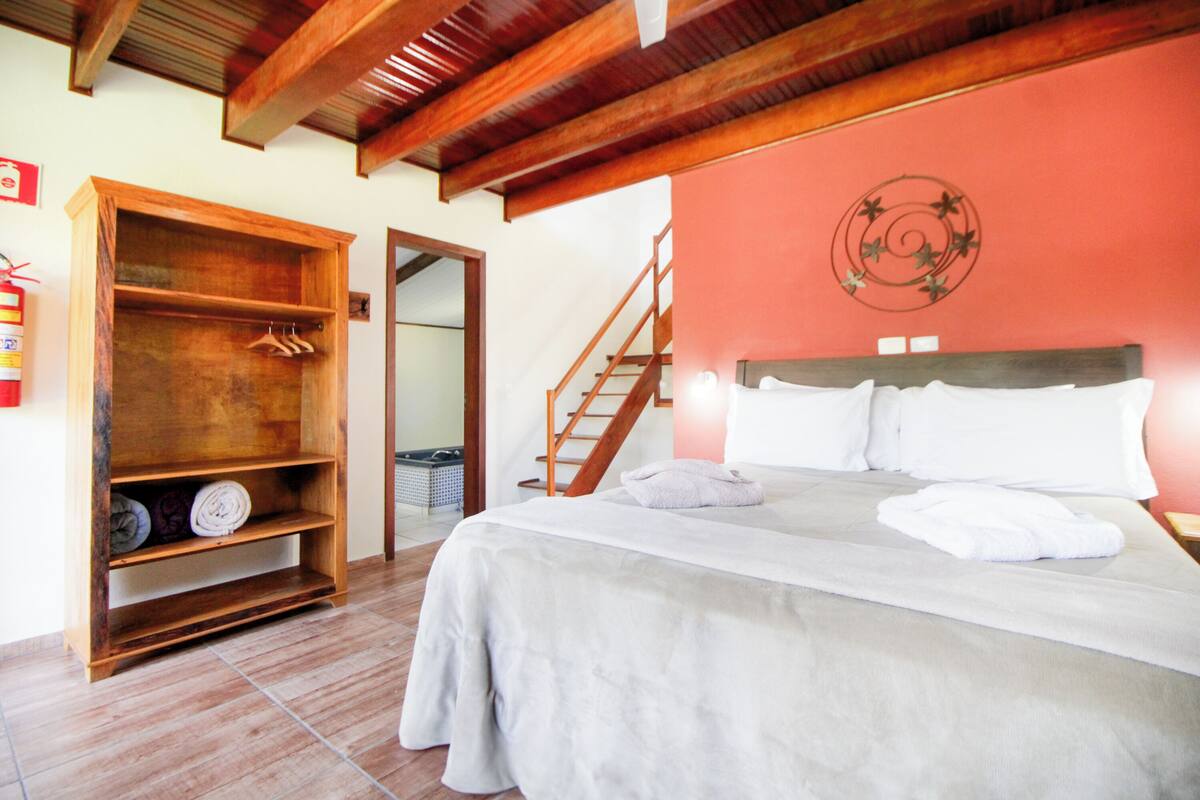Un dormitorio con una cama, un armario de madera, una escalera y un adorno en la pared.