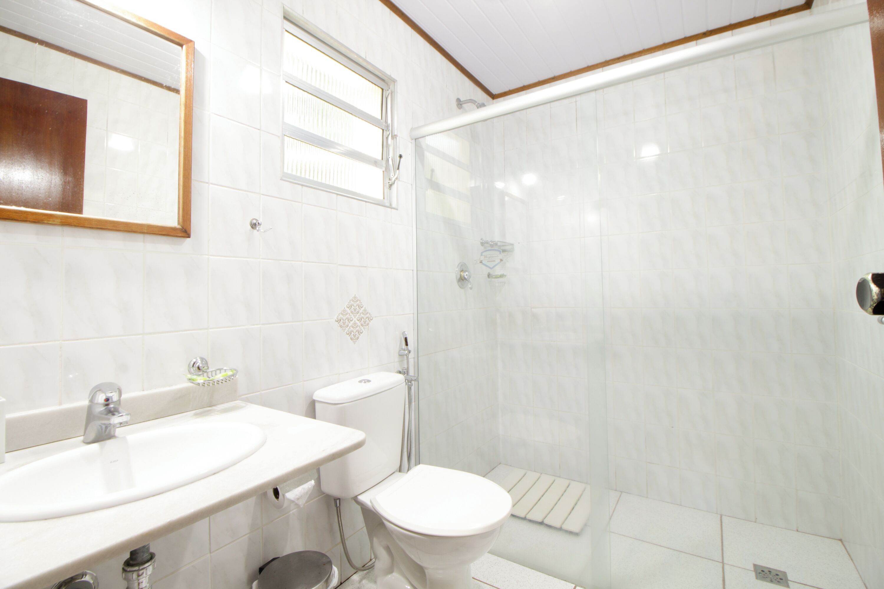 A bathroom with a sink, toilet, and glass shower enclosure.
