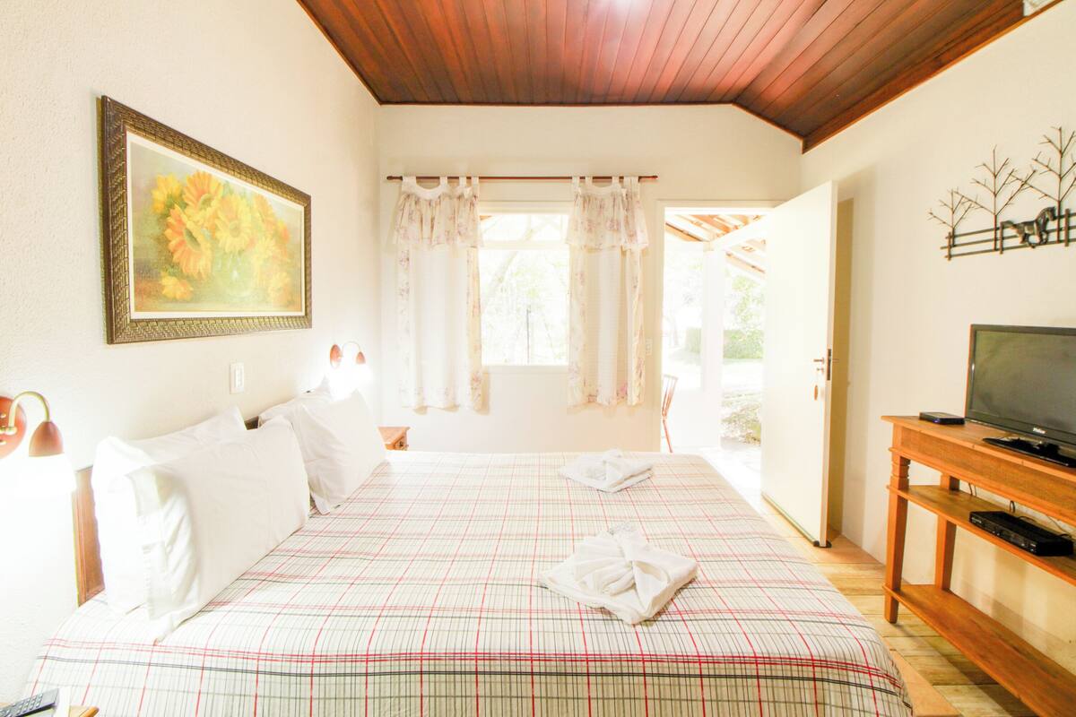 Habitación de hotel con una cama, un televisor y un cuadro en la pared.