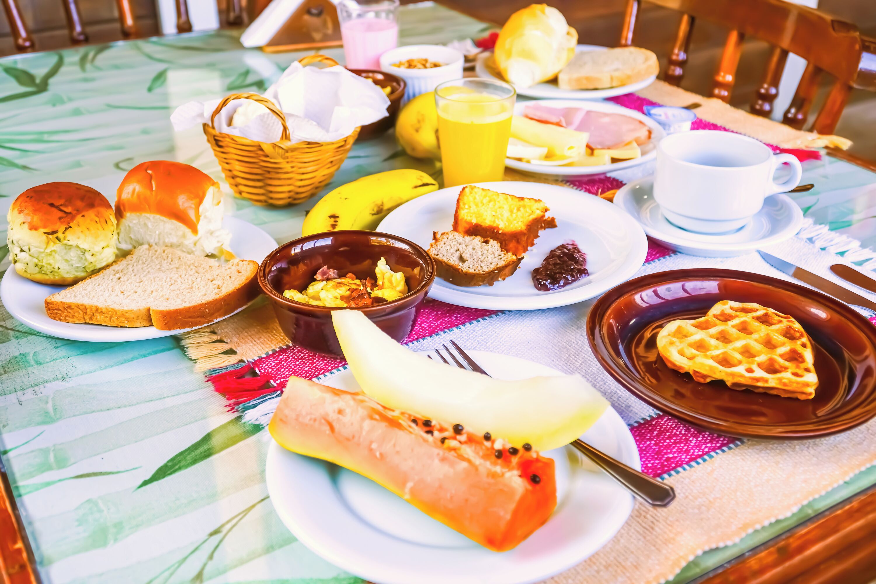 Una mesa de desayuno con diversos alimentos, incluyendo pan, gofres y una banana.