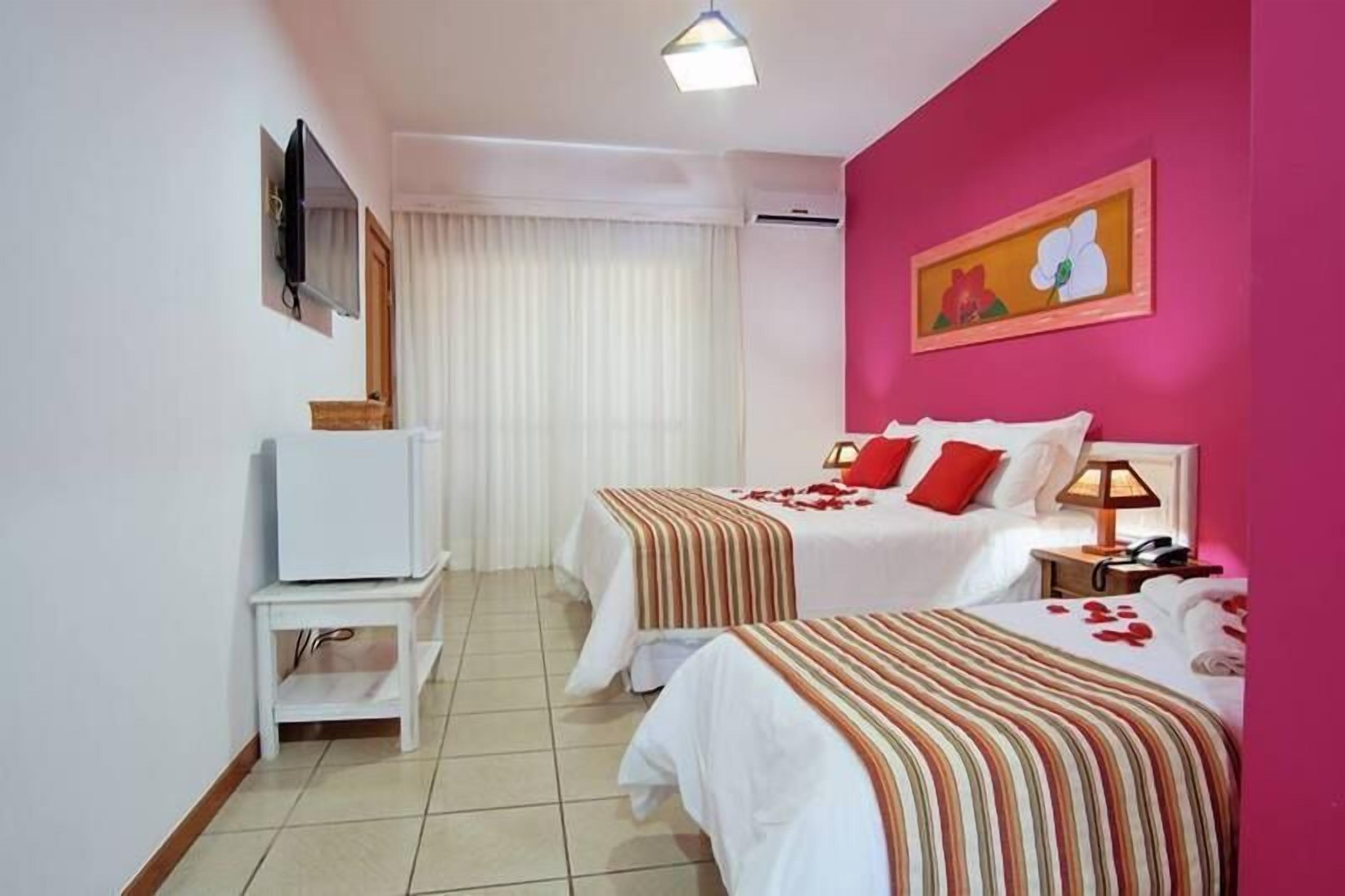 Habitación de hotel con dos camas, un televisor, una mesita y un cuadro en la pared.