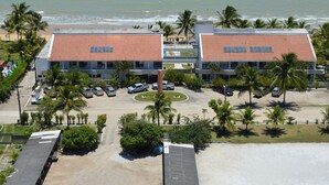 A hotel with a parking lot, a beach view, and palm trees.