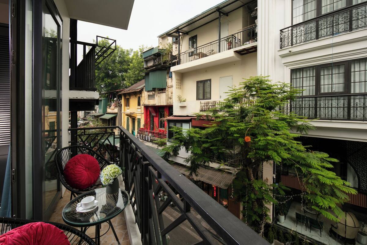 A balcony with a glass table, chairs, and a potted plant.