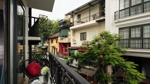 A balcony with a glass table, chairs, and a potted plant. - Hanoi La Palm Boutique Hotel (Hanoi)
