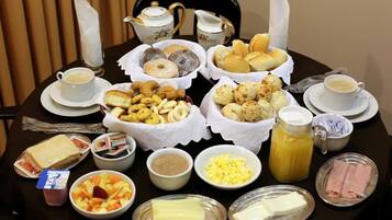 A breakfast spread with various pastries, sandwiches, and beverages on a table.