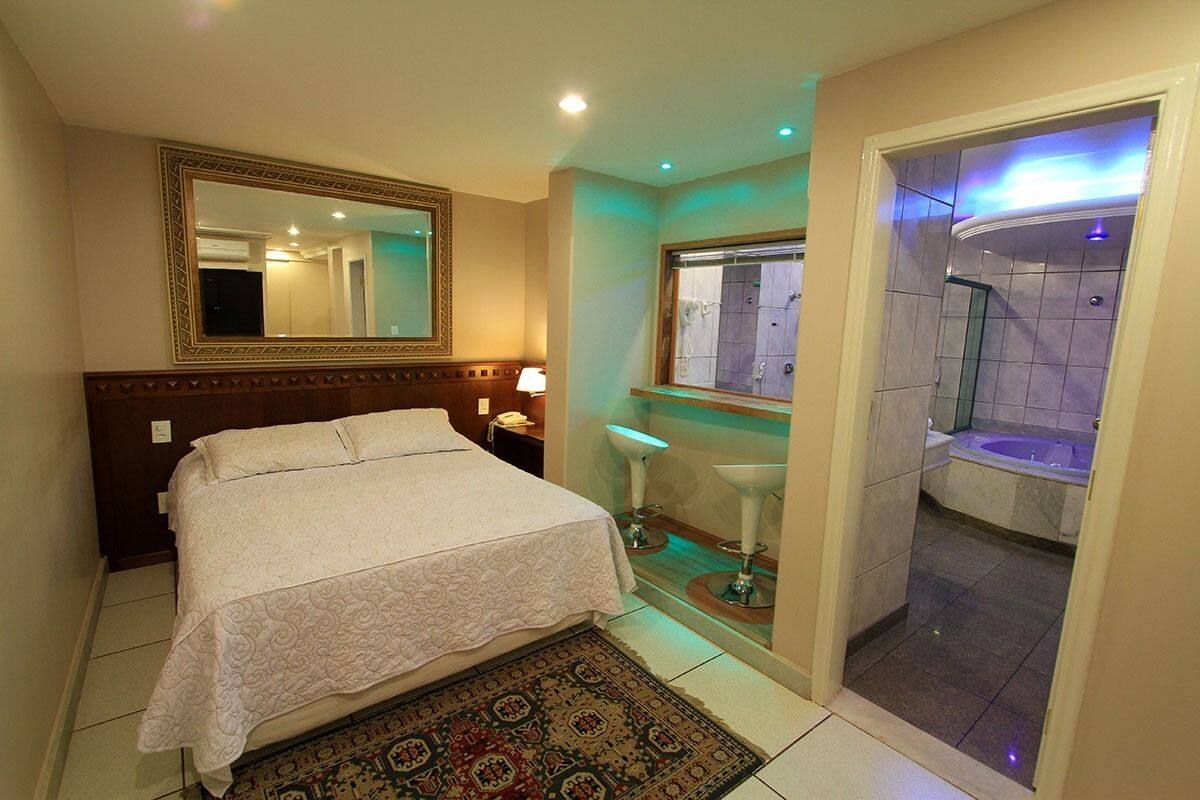 Une chambre d’hôtel comprenant un lit, un miroir, une salle de bain avec une baignoire et une douche.