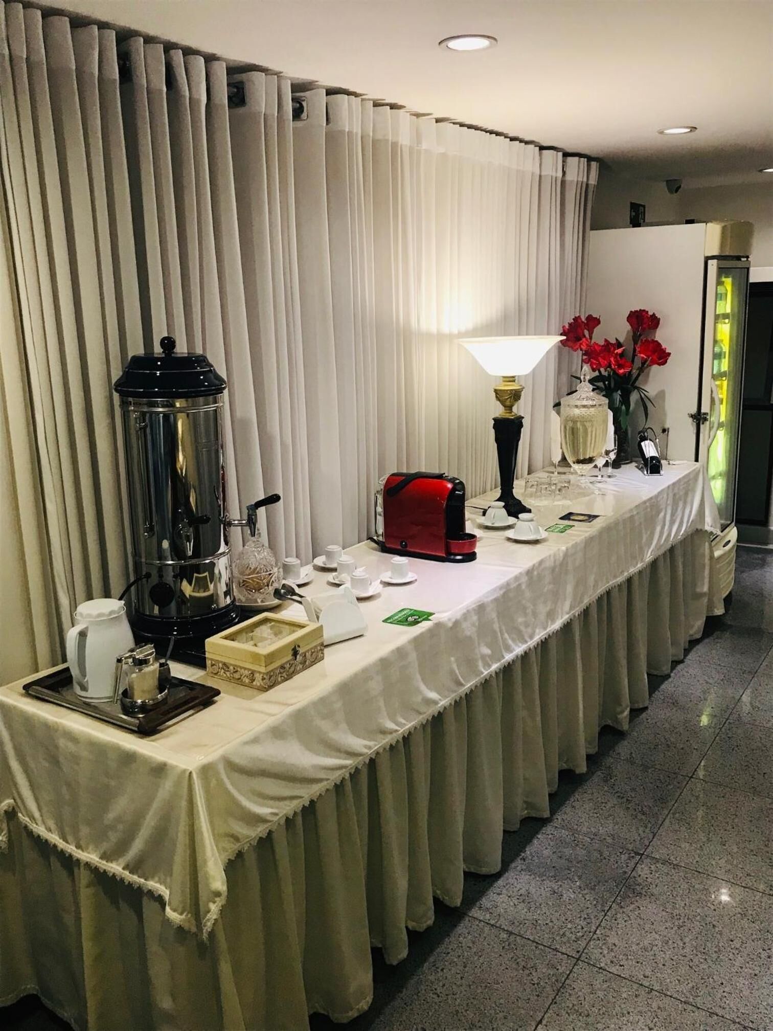 A buffet setup with a coffee station, a red cash register, and a floral centerpiece.