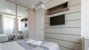 A hotel room with a bed, a television mounted on the wall, and a mirror. - Pousada Costão dos Ingleses (Florianopolis)