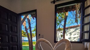 A bed with a heart-shaped towel arrangement and scattered purple flowers. - Pousada dos Coqueiros (Ipojuca)