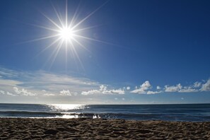 Een strand met zand en zee, onder een heldere lucht.