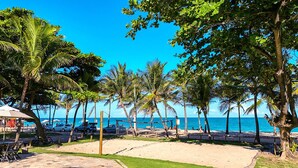 A pool area with a clear view of the ocean and palm trees. - Pousada dos Coqueiros (Ipojuca)