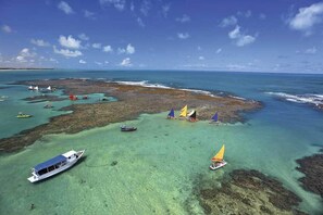 Een kustgebied met helder turquoise water, boten en een rotsachtige kustlijn.