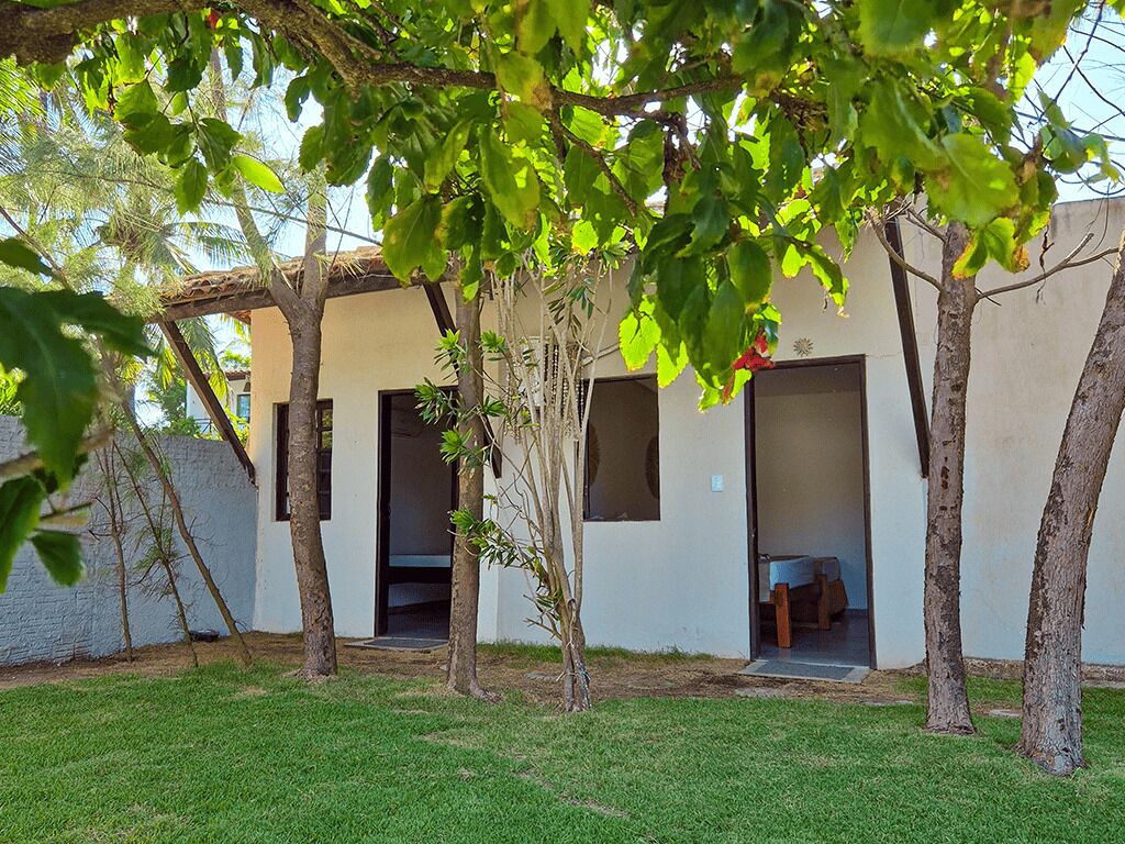 Un edificio con varias puertas abiertas, rodeado de árboles y un césped.