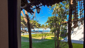 A view of a well-maintained lawn with a pool, palm trees, and a clear blue sky. - Pousada dos Coqueiros (Ipojuca)
