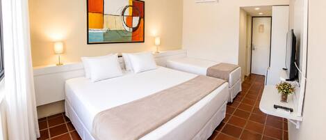 A hotel room with a large bed, a smaller bed, a TV, and a painting on the wall.