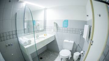 Un baño con cabina de ducha de vidrio, un lavamanos blanco con espejo, inodoro y bidé.