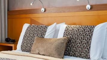 A hotel room with a bed, two bedside lamps, a nightstand with a camera, and a magazine.