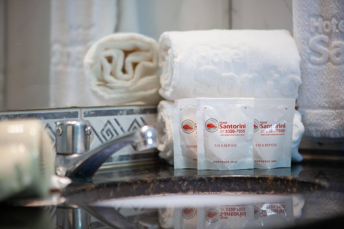 A bathroom with a sink, a towel, and three bottles of shampoo.