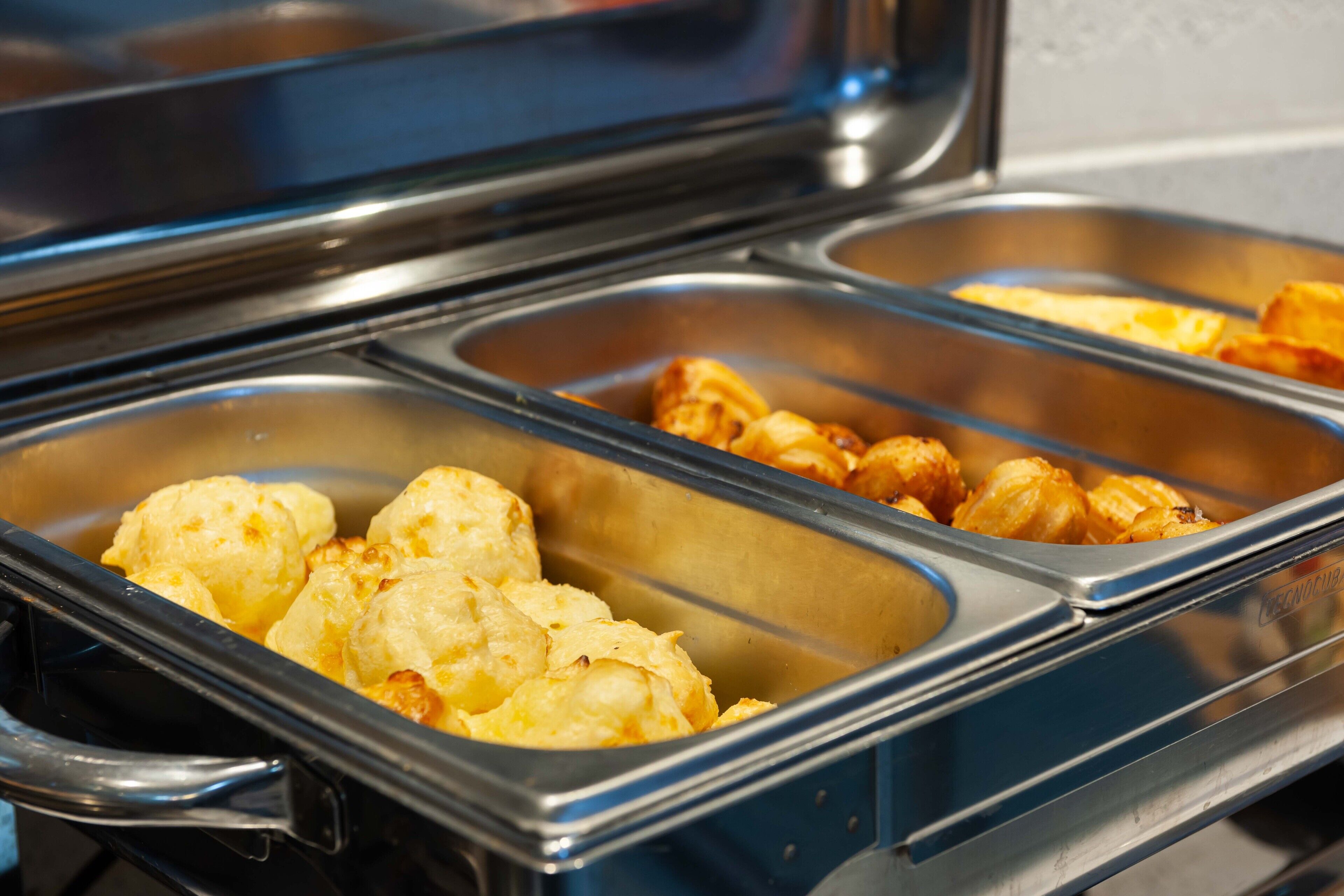Un bufé con diversos alimentos, incluyendo patatas y coliflor asadas.