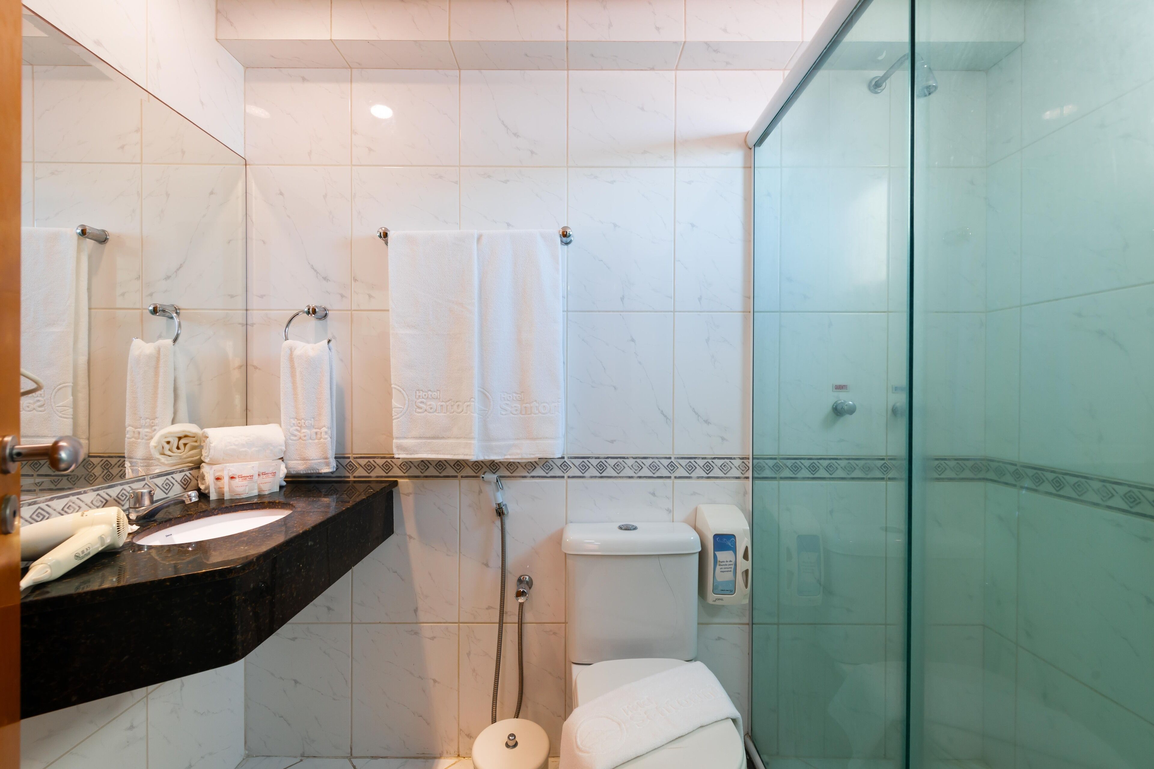 A modern bathroom with a marble sink, a glass shower enclosure, and a toilet.
