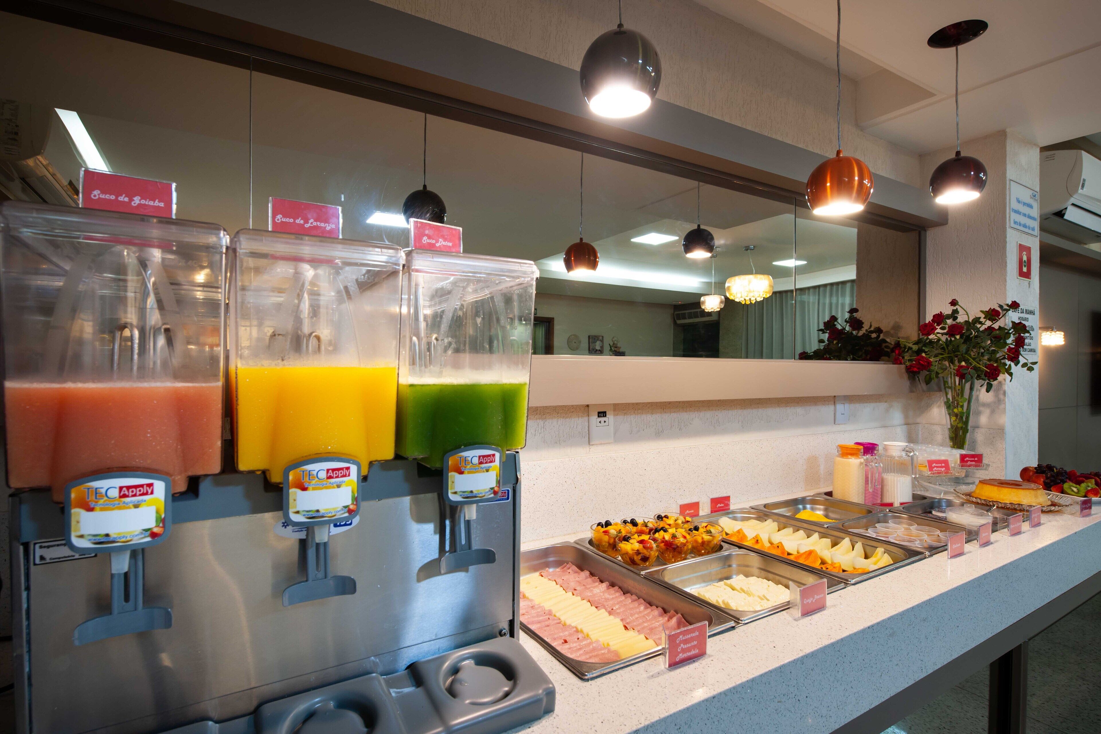 Uma área de buffet com diversas opções de comida e um dispensador de sucos.