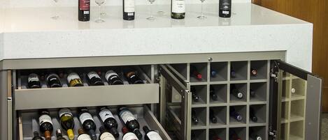 Un espace dédié à la dégustation de vins, avec des bouteilles et des verres disposés sur un comptoir et un présentoir à vin en dessous.