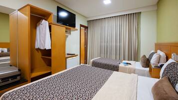 Habitación de hotel con dos camas, un televisor, un armario y un escritorio con computadora.