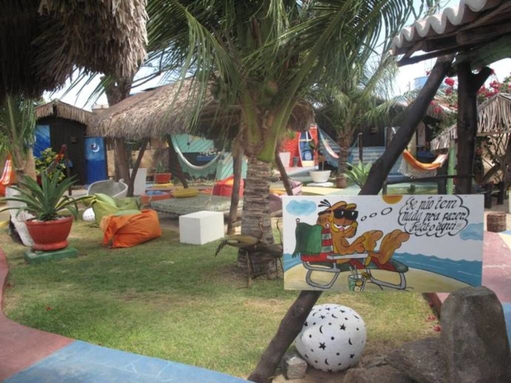 Uma área de resort tropical com palmeiras, cabanas de palha e uma rede.