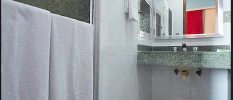 A bathroom with a shower, a sink with a mirror, and a red towel hanging on the wall.