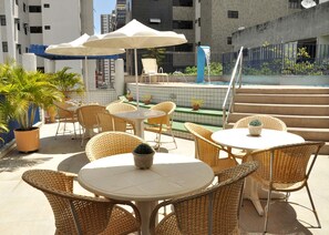 An outdoor patio with wicker tables and chairs, a small pool, and potted plants. - Vila Azul Praia Hotel (Fortaleza)