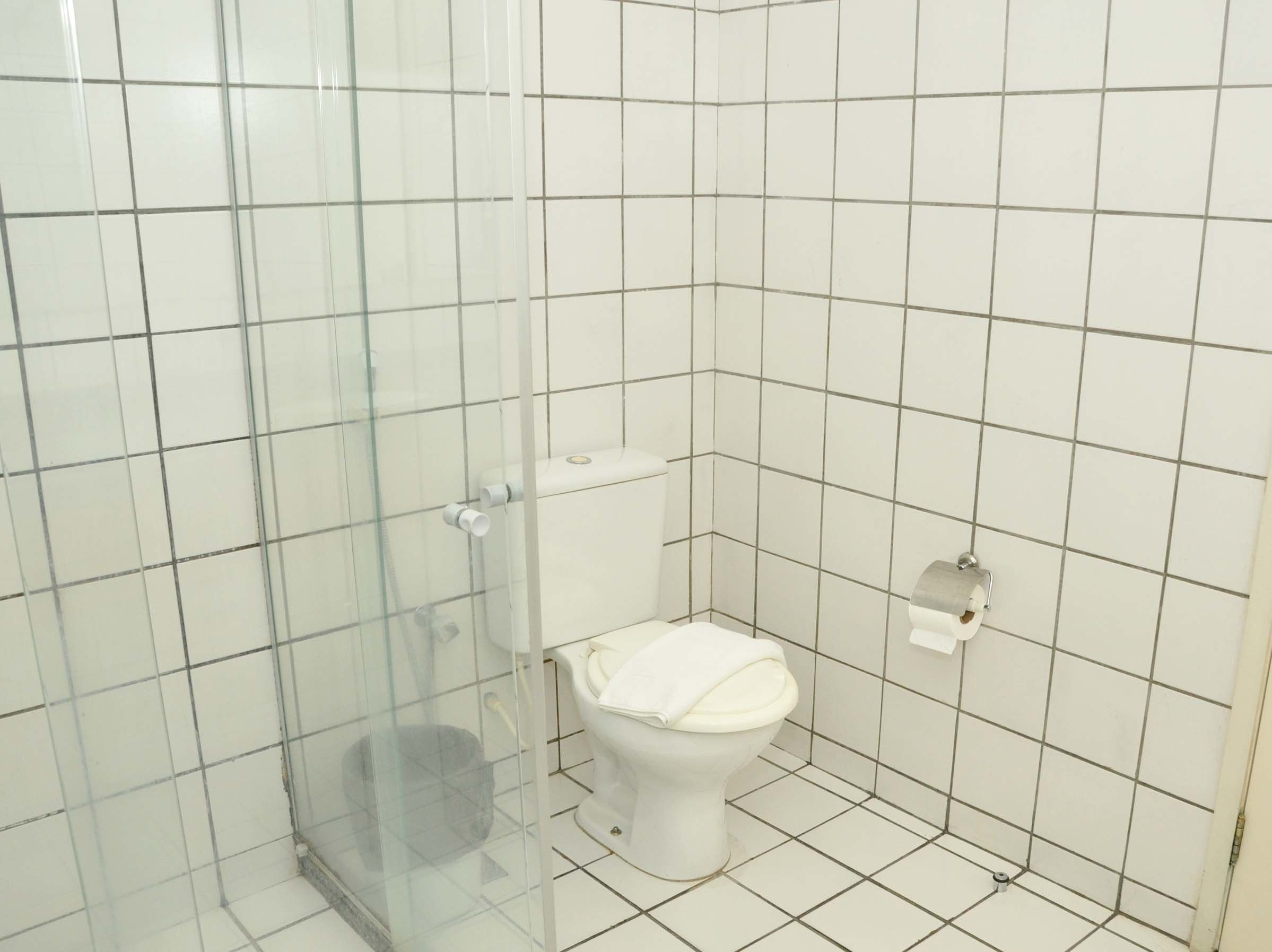 A bathroom with a glass-enclosed shower, a white toilet, and a tiled floor.