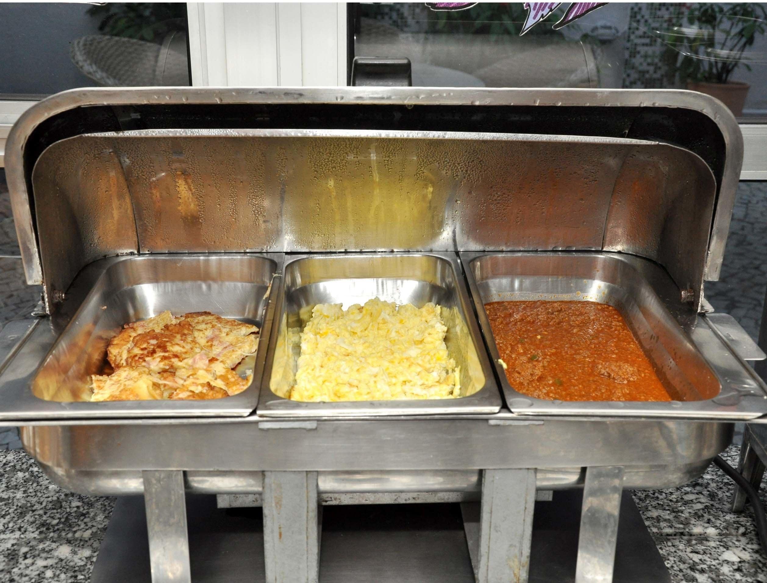 Un buffet avec trois plateaux en métal contenant différents plats.