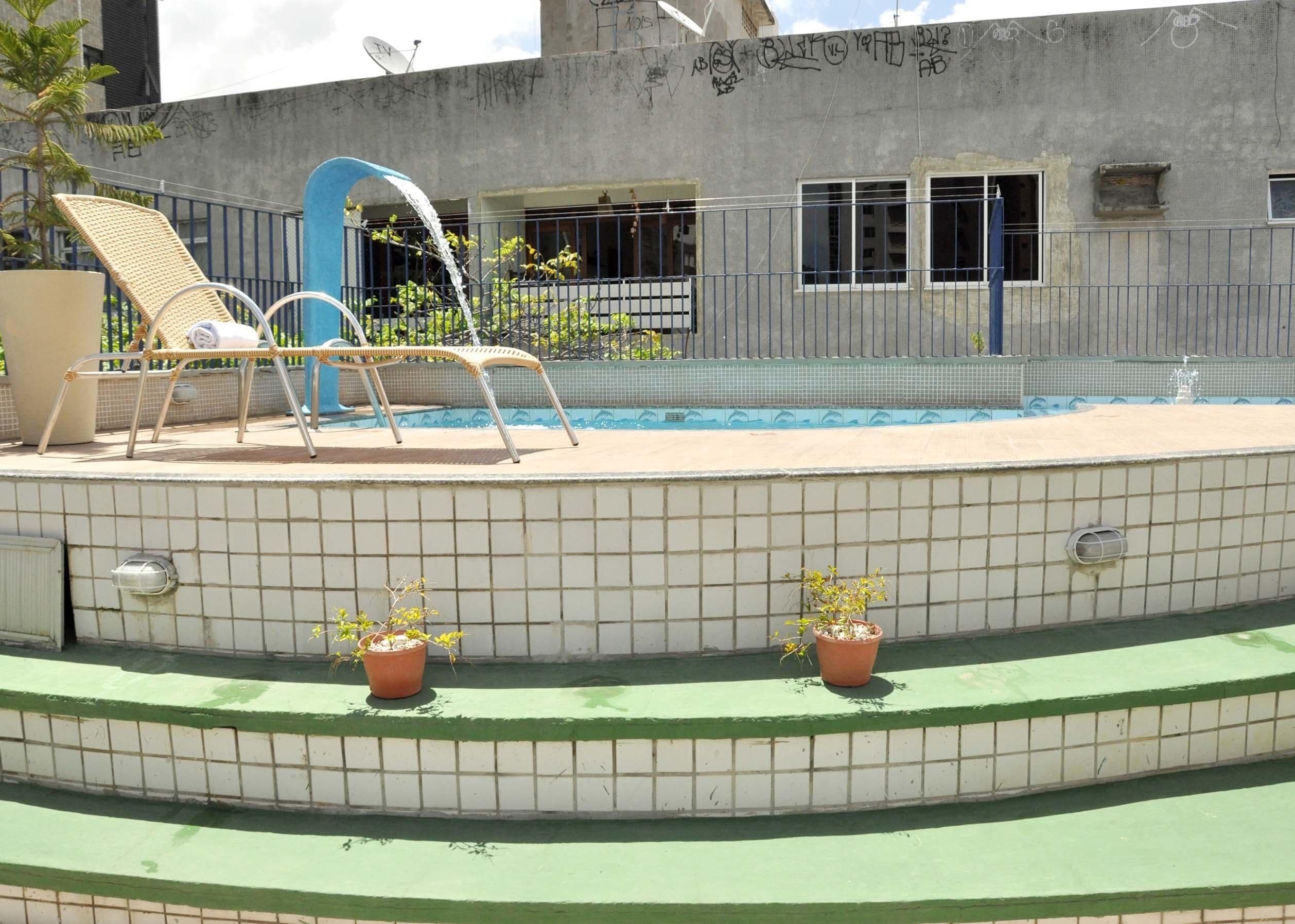 A swimming pool with two lounge chairs and two potted plants.