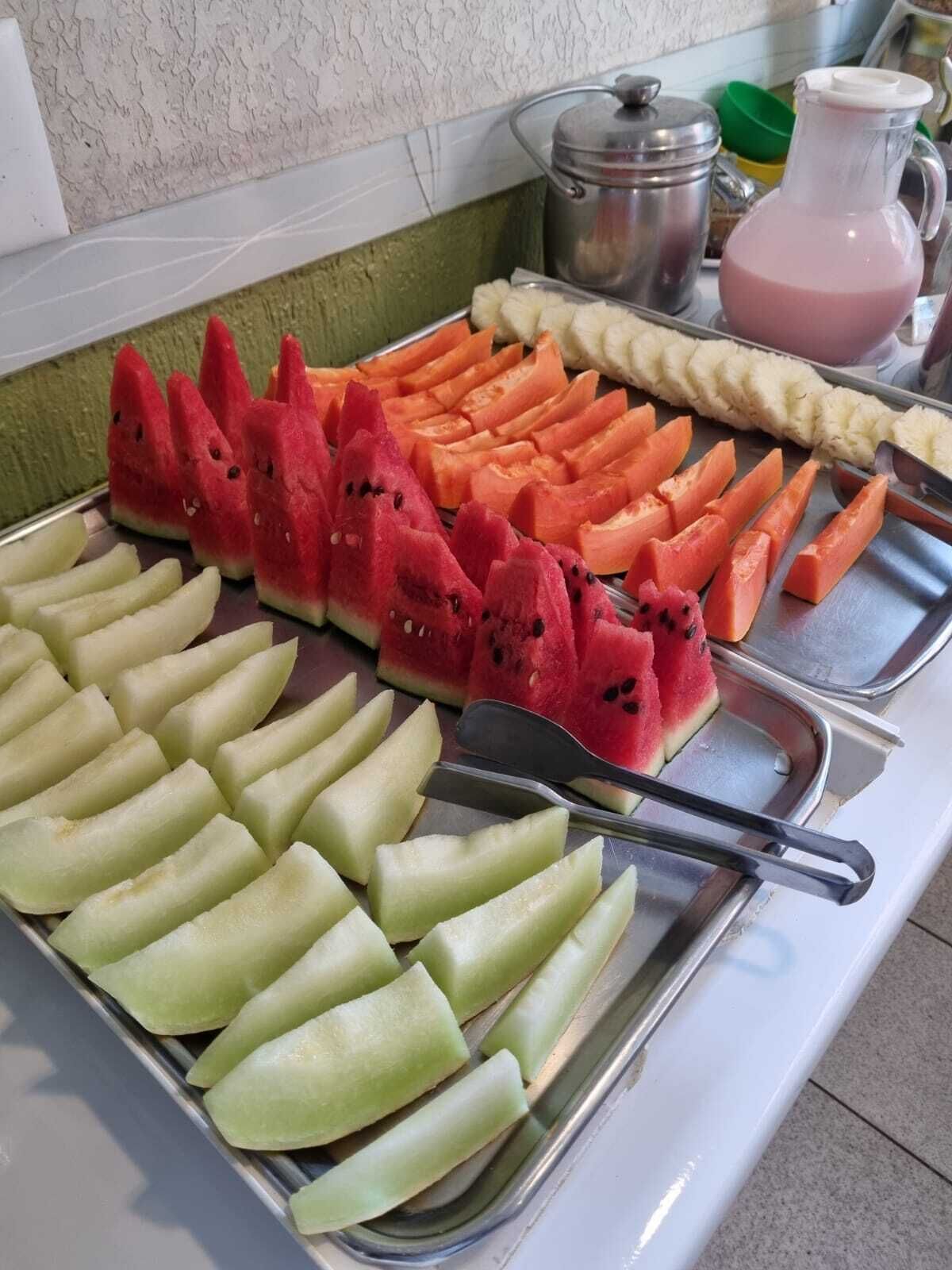 A buffet with various fruits and a pitcher of pink drink.