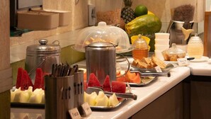 Un bufé con diversas opciones de comida, incluyendo frutas, una estación de café y un cartel que indica una sala privada.