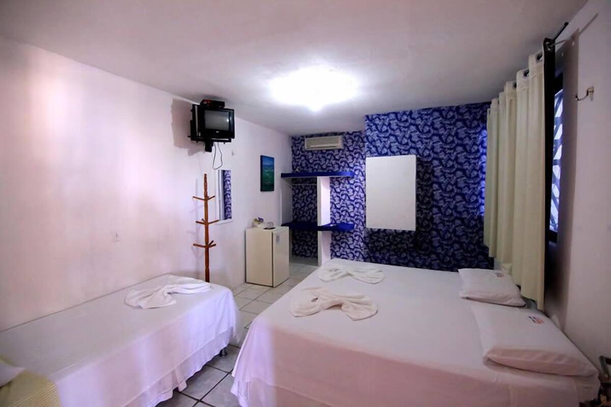 Hotellihuone, jossa on kaksi sänkyä, televisio, minibaari ja kuviollinen seinä.